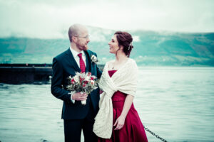 The bride and groom pose for a wedding photograph in front of Carlingford Lough at a micro wedding in Ireland
