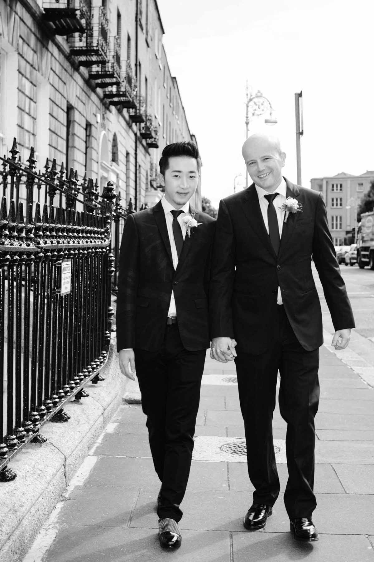 LGBT wedding photographer photographs two grooms walking through Dublin on their wedding day