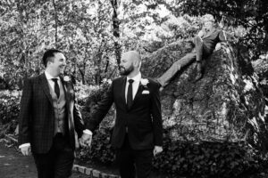LGBTQ Wedding Photography of two grooms in front of the Oscar Wilde Statue in Merrion Square Park in Dublin on their wedding day.