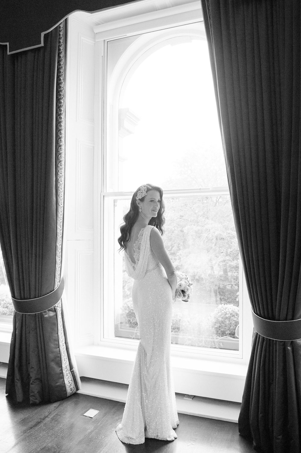 The bride poses for a bridal portrait by a window at The Shelbourne Hotel in Dublin