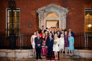 Guests at a Merrion Hotel wedding pose for a group photograph on the steps of the hotel